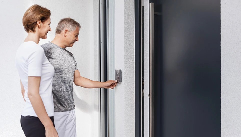 Paar bedient ein elektronisches Türschloss an der Haustür