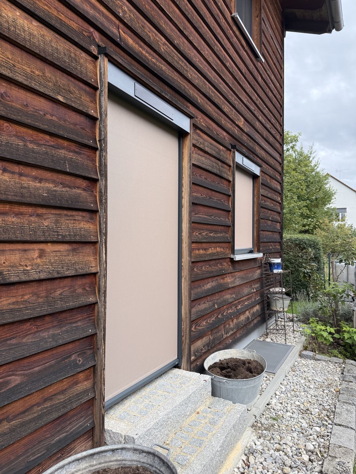 Zip-Screens an zwei Fenstern der Hausfassade